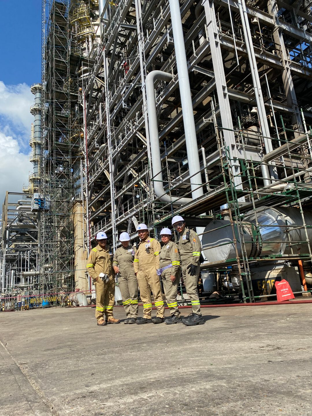 Equipo de ILN con cascos reunido frente a estructuras de una planta industrial