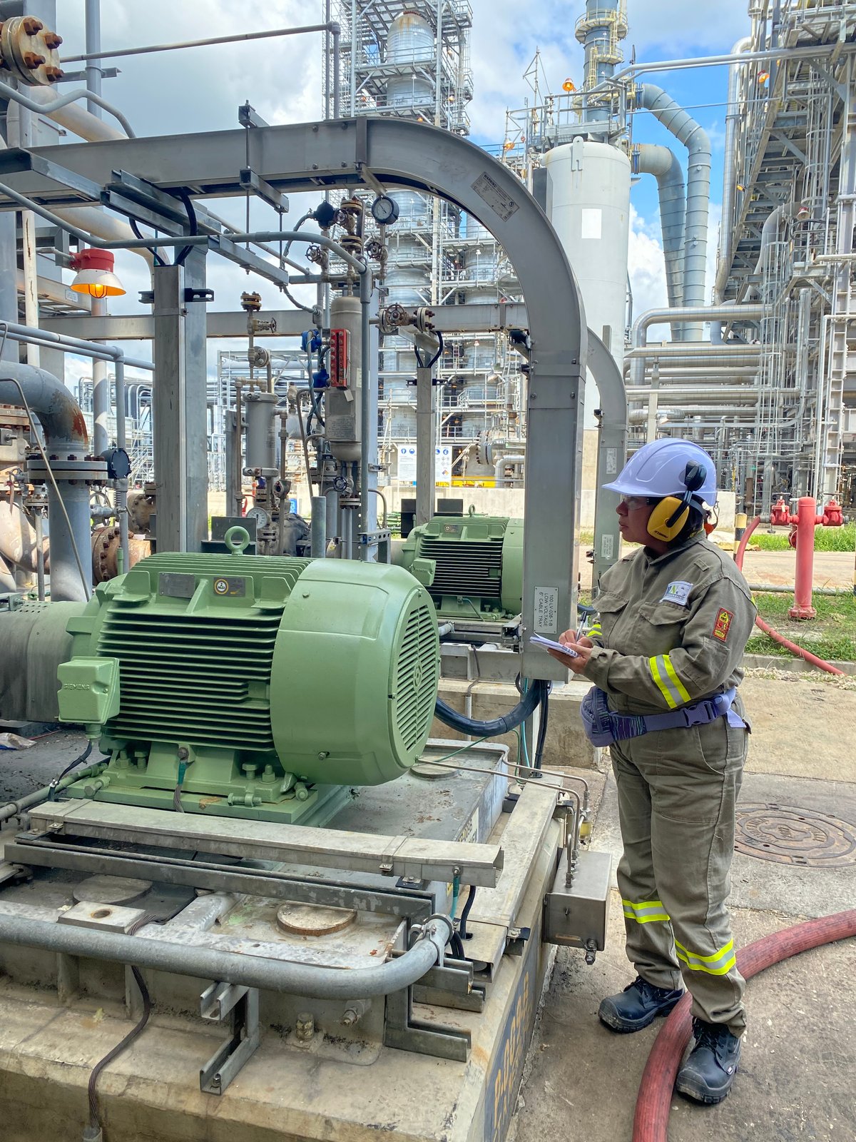 Profesional de ILN revisa información junto a un motor y equipo de bombeo industrial