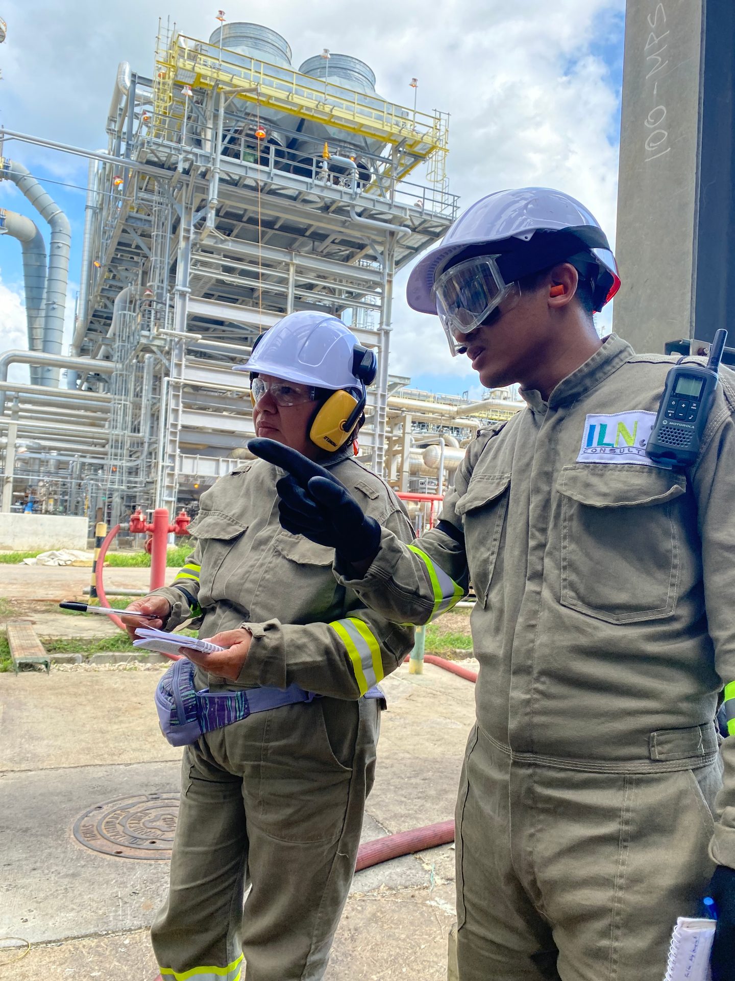 Dos profesionales de ILN con elementos de protección revisan documentación y coordinan actividades en una instalación industrial