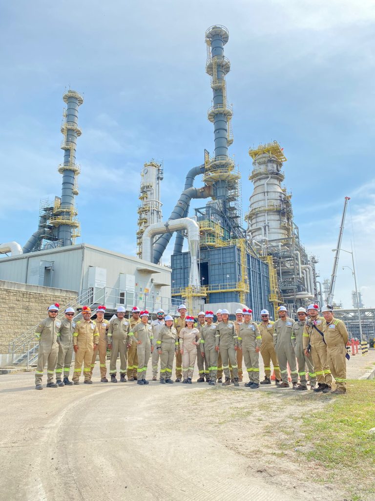 Equipo con elementos de protección personal reunido frente a una instalación industrial