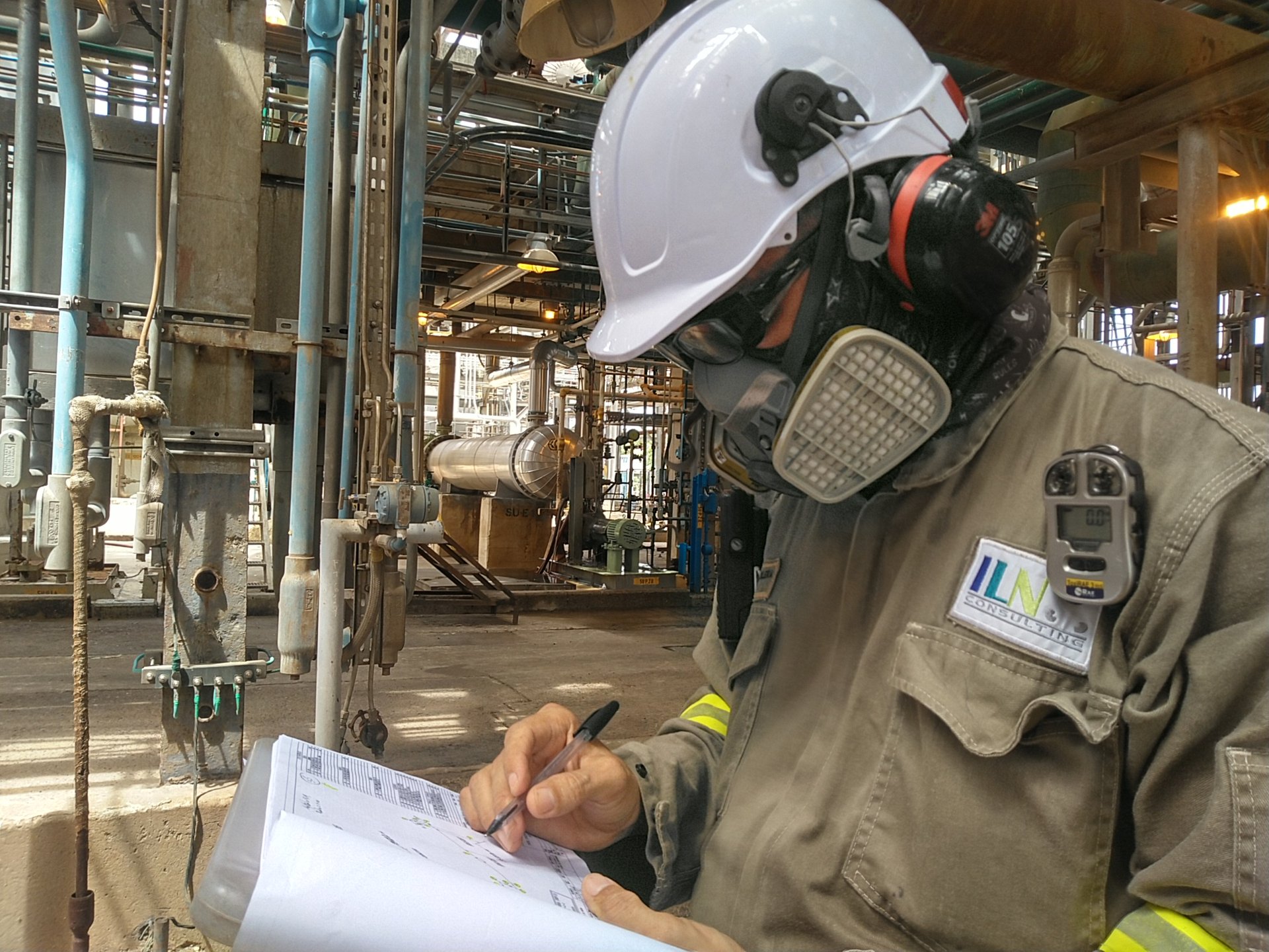 Profesional de ILN con elementos de protección personal registra información técnica en una instalación industrial