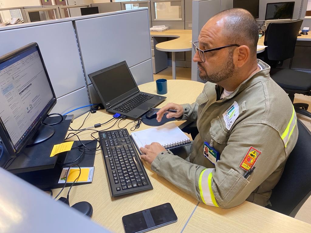 Profesional de ILN trabaja con un computador y documentación en un puesto de oficina